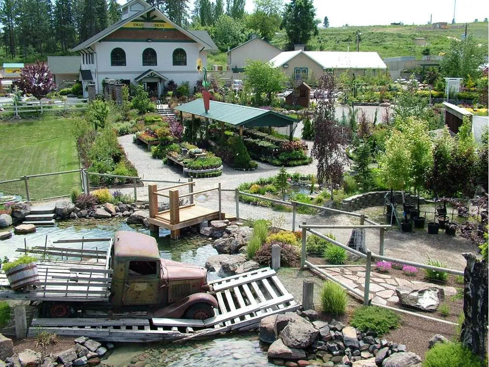 Elevated view of garden beds, winding paths and a vintage truck by a pond