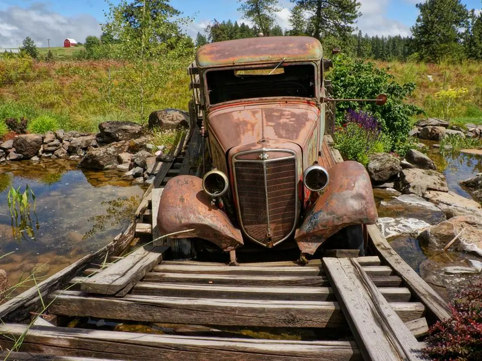 Front of a rusted vintage truck displayed on a wooden bridge