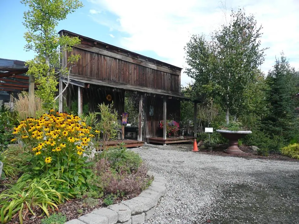 Rustic wooden building beside a curved gravel path and flowering garden