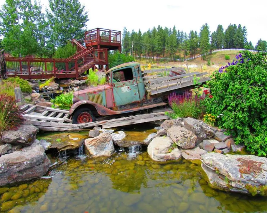 Vintage truck displayed on a wooden bridge over a rock-lined pond