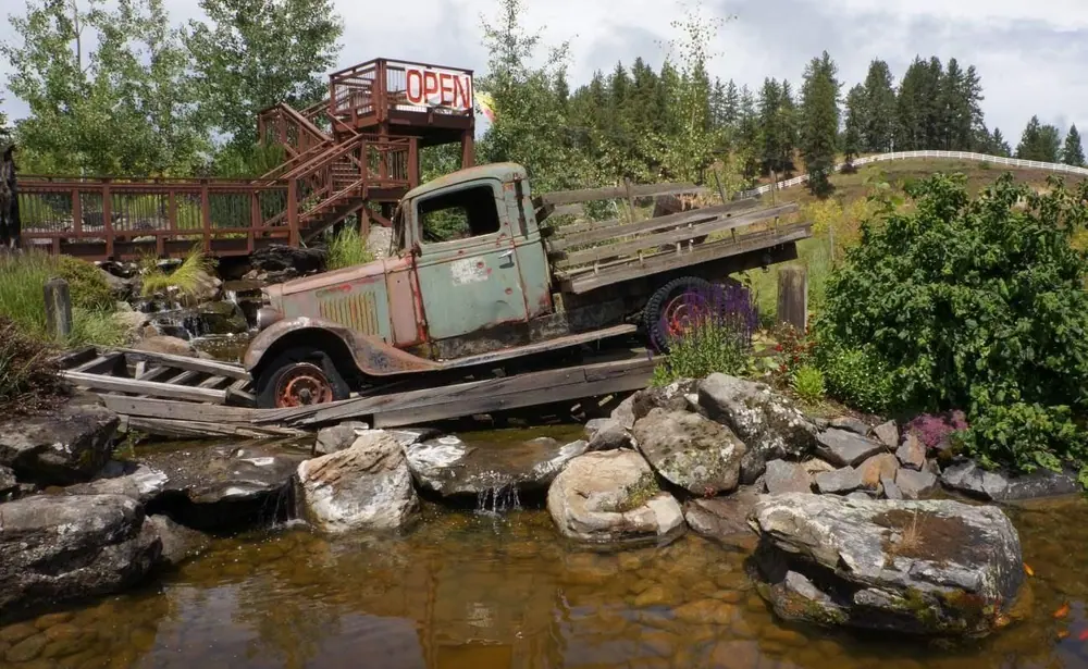 Vintage truck displayed on a timber bridge over a rock-lined pond